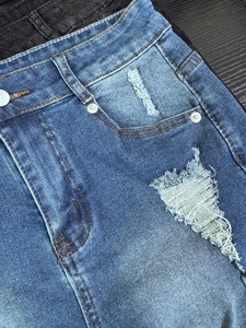 Detalle de pantalones cortos vaqueros de talle alto con remaches y textura rasgada