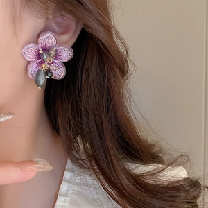 Gros plan sur une boucle d'oreille fleur brodée violette élégante avec perles en cristal