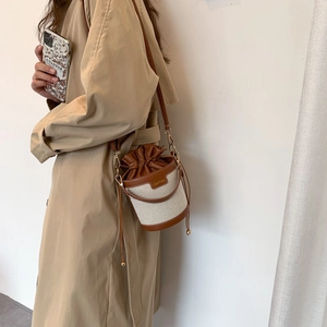 Brown and beige patchwork bucket bag with drawstring and adjustable strap on a model