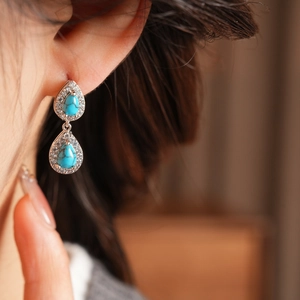 Macro detail of silver drop earrings featuring vibrant turquoise stones and zircon accents