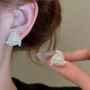Detail of triangle stud earrings with white pearls and crystals worn on ear
