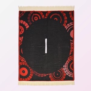 Detailed flat lay of a black and red jacquard poncho with elegant white tassel fringes