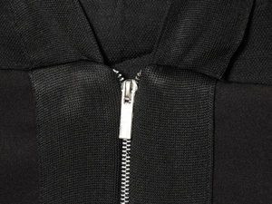 Primer plano de una cremallera metálica plateada en vestido de punto negro