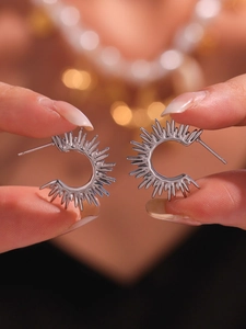 Detailed close-up of sunburst silver stud earrings with a sleek metallic finish