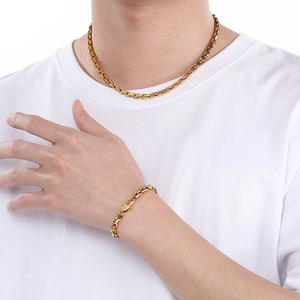 Golden stainless steel link chain necklace and bracelet set shown on a female model
