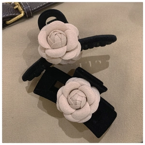 Detail of elegant black velvet hair claws with stereoscopic beige camellia flower texture