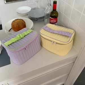 Detailed macro view of quilted makeup bags with vibrant frilled handles and zippers