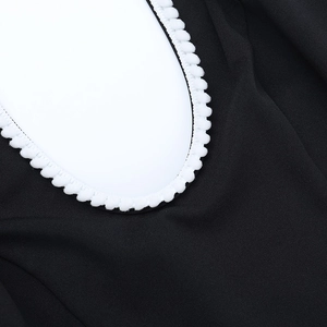 Détail de la robe noire avec bordure contrastée à pompons blancs sur l'encolure en U