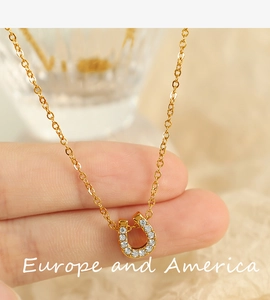 Makroaufnahme einer goldenen Hufeisenkette mit weißen Kristallen zwischen Fingern