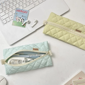 Detailed macro view of quilted pastel stationery pouches with zippers and woven side handles