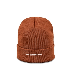 Close-up of caramel brown knit beanie featuring white NOT INTERESTED embroidery