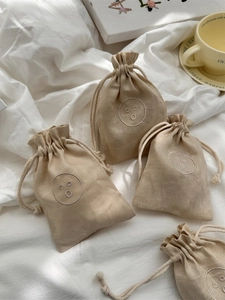 Detailed macro view of linen drawstring bag with embroidered smiley face on cotton fabric
