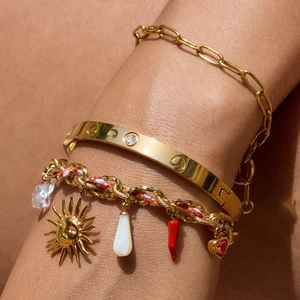 Gold chain and cord bracelets set with sun, chili, and heart charms worn by model