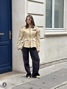 Detail of beige jacket with black leather trim and waist-cinching hourglass silhouette