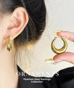 Detailed view of thick gold titanium steel hoop earrings on model with polished finish