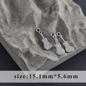 Macro shot of silver guitar pendants with inlaid zircons on rock, size 15.1mm x 5.6mm