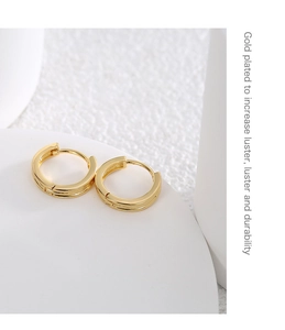 Detail of gold-plated round hoop earrings showcasing a polished finish on stone display