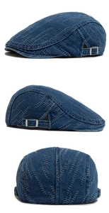 Detailed view of dark blue denim beret with light blue stitching and metal side buckle