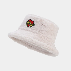 Détail du patch brodé en forme de cœur et de lettres sur le bob en peluche douce