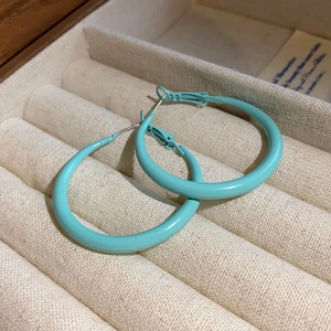 Close-up of vintage Tiffany blue hoop earrings displayed in a beige jewelry box