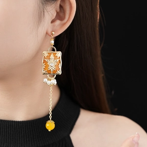 Detail of vintage flower earring with amber resin pendant and pearl tassel on model