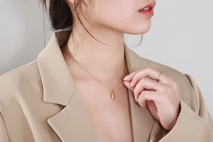 Détail d'un collier doré avec pendentif pièce de monnaie ovale au design vintage