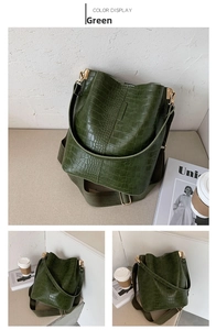 Detail of green crocodile pattern bucket bag with wide knit strap and gold hardware