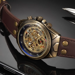 Close-up of bronze skeleton watch dial with leather rivet strap on dark surface