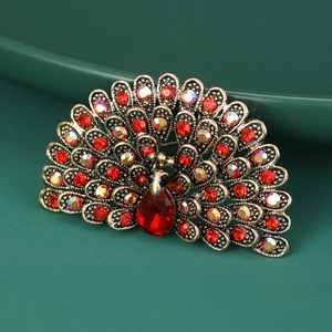 Detail of vintage peacock brooch with colorful crystals on a green ceramic plate