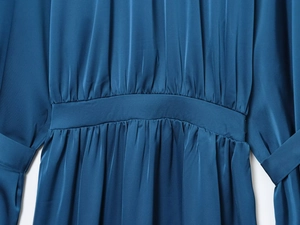 Detailed view of dark blue satin dress featuring elegant waist pleats and fabric texture