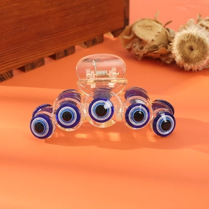 Detail of transparent shark hair claw clip featuring blue evil eye patterns and spring