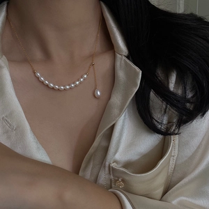 Close-up of freshwater pearl necklace with gold chain on model wearing silk shirt