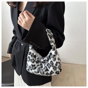 Close-up of fluffy leopard print crescent bag held by a model in a black blazer