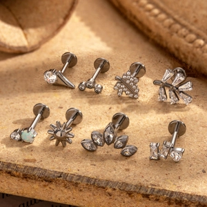 Macro detail of G23 titanium labret studs with zircon and opal set on a cork background