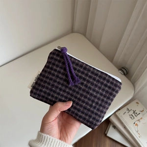Close-up of plaid fabric coin purse featuring purple tassel zipper and Simple Wish label