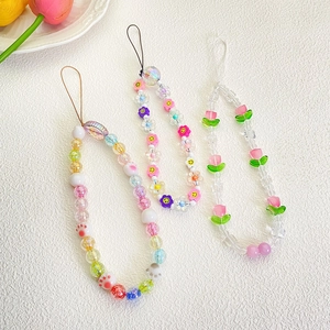 Detail of beaded phone straps with colorful charms like flowers and smiley faces
