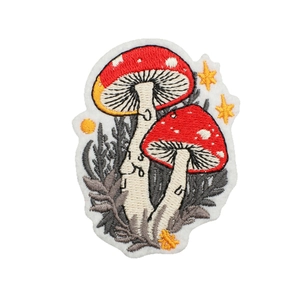 Detailed mushroom embroidery patch with red and white cap on a clean white background