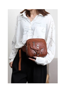 Détails d'un sac bandoulière vintage en cuir marron avec rivets argentés et bandoulière