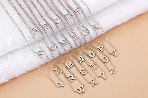 Detailed view of silver capital letters pendants with micro-paved zircons on thin chain