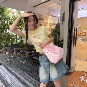 Outdoor street style view of a pink heart pattern canvas tote bag with a denim skirt