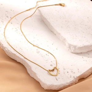 Elegant gold snake chain necklace with hollow heart pendant on white stone and satin
