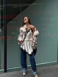 Detail of white satin camisole with black lace and luxury faux fur jacket with wide cuff jeans