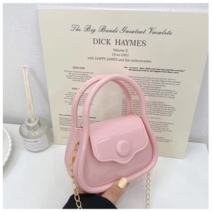 Pink mini jelly bag with semi-circular handle and gold chain strap in detail view