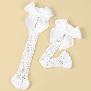 Close-up of white mesh socks featuring large satin bows for girls on a beige background