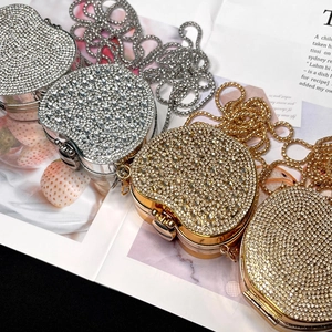Close-up of heart-shaped rhinestone mini bags in gold and silver with metal chain straps