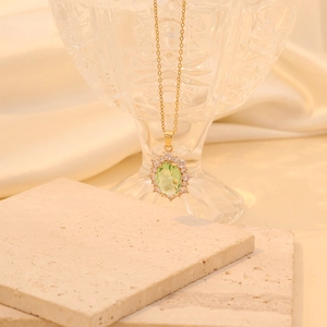 Close-up of gold stainless steel necklace featuring a green oval crystal pendant with diamonds