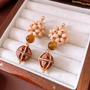 Ethnic drop earrings with wooden woven beads and amber pendants in a jewelry box