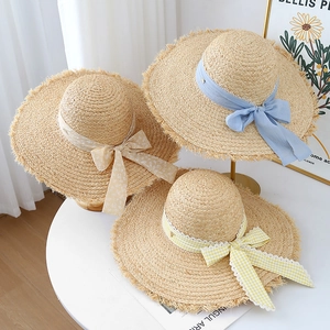 French woven raffia sun hat with wide frayed brim and decorative bow ribbons