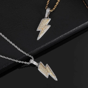 Detail of lightning bolt pendants with zircon inlay in gold and silver hip hop style
