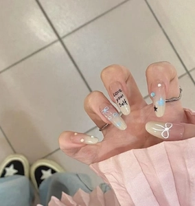 Detail of gradient press-on nails with white 3D bows, stars, and rhinestones design